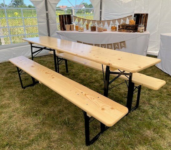 Die klassische Bierzeltgarnitur in Natur wird für eine Party verwendet und befindet sich in einem Festzelt.