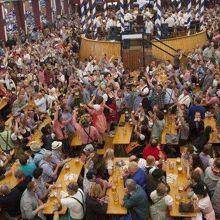 Viele Tische und Bänke der Bierzeltgarnitur mit Beinfreiheit beim vollen Oktoberfest.
