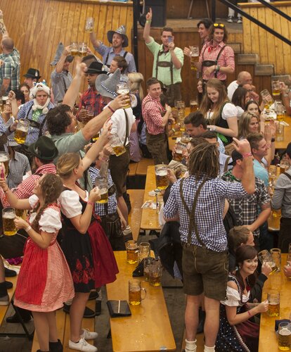 Man sieht einen Schnappschuss vom Oktoberfest, Hunderte von Menschen stehen auf den RUKU1952 Classic Bierzeltgarnituren und feiern und tanzen. Die stabilen Bierbänke und -tische halten das aus.