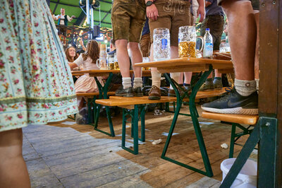 Mehrere Personen stehen beim Oktoberfest auf den Bierbänken mit Beinfreiheit.