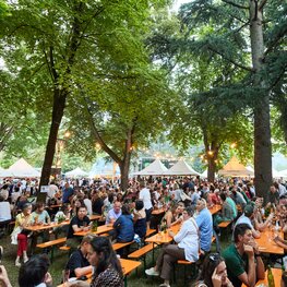 Die Besucher des Street Food Festivals haben auf den klassischen Bierzeltgarnituren Platz genommen und genießen die Veranstaltung.