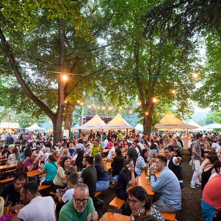 Die Besucher des Street Food Festivals haben auf den klassischen Bierzeltgarnituren Platz genommen und genießen die Veranstaltung.